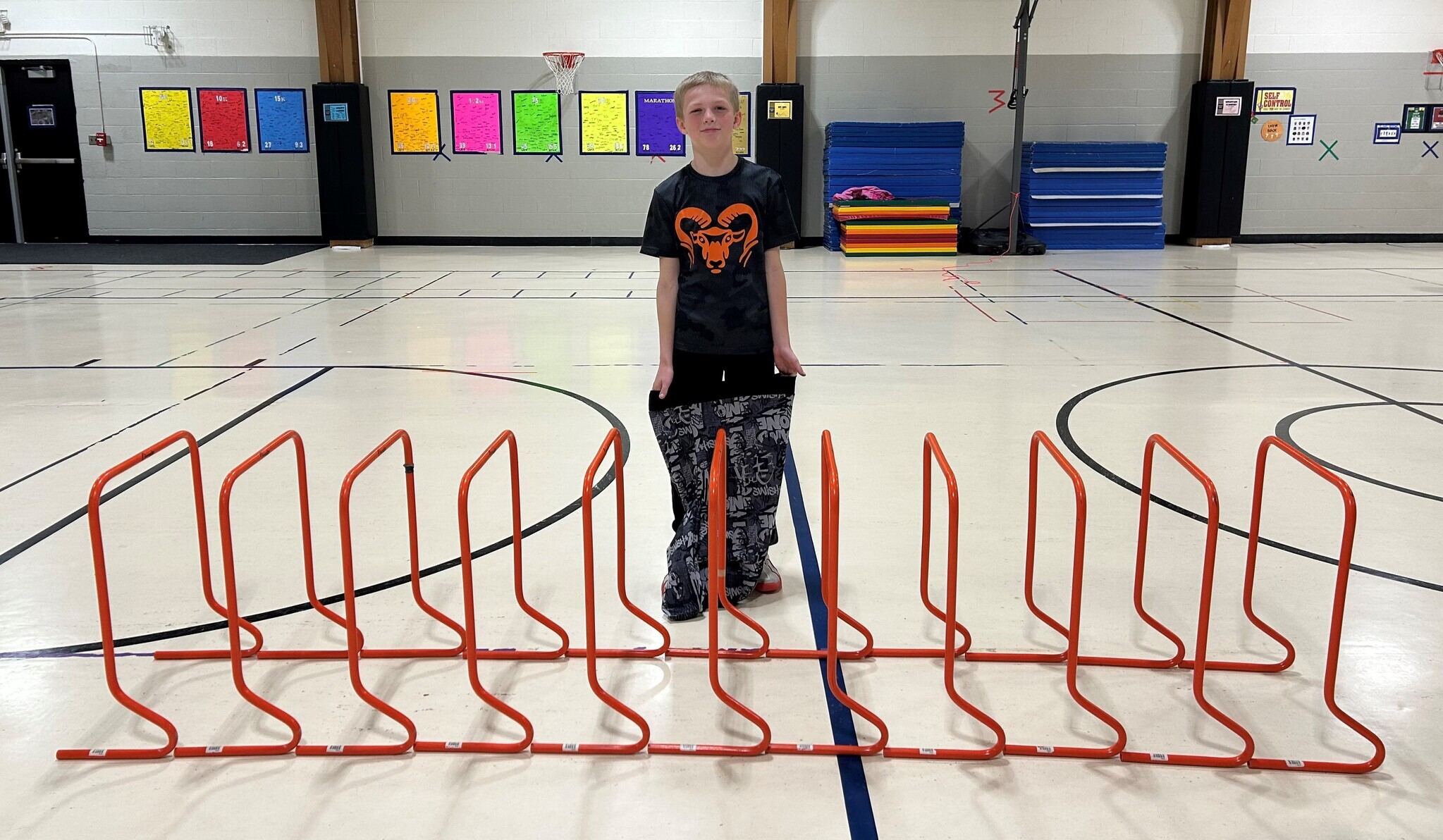 Student with blond hair standing by 11 hurdles