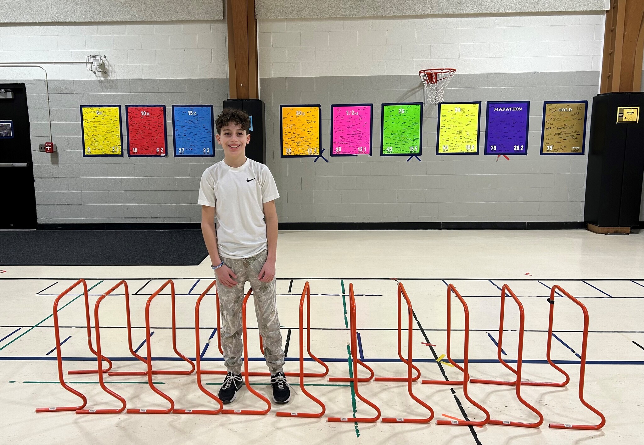 Upper Elementary student with dark hair standing by 11 orange hurdles