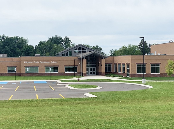 Edgerton Trails Elementary School Building. Brown brick building with a grey roof on the tall entrance area